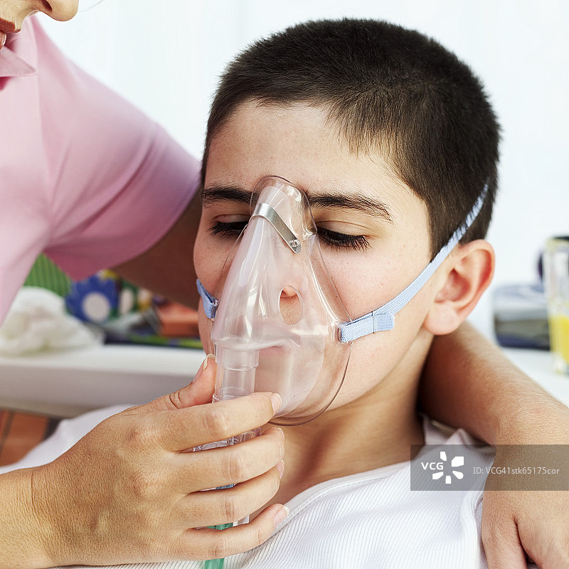 母亲在儿子脸上罩着氧气面罩图片素材