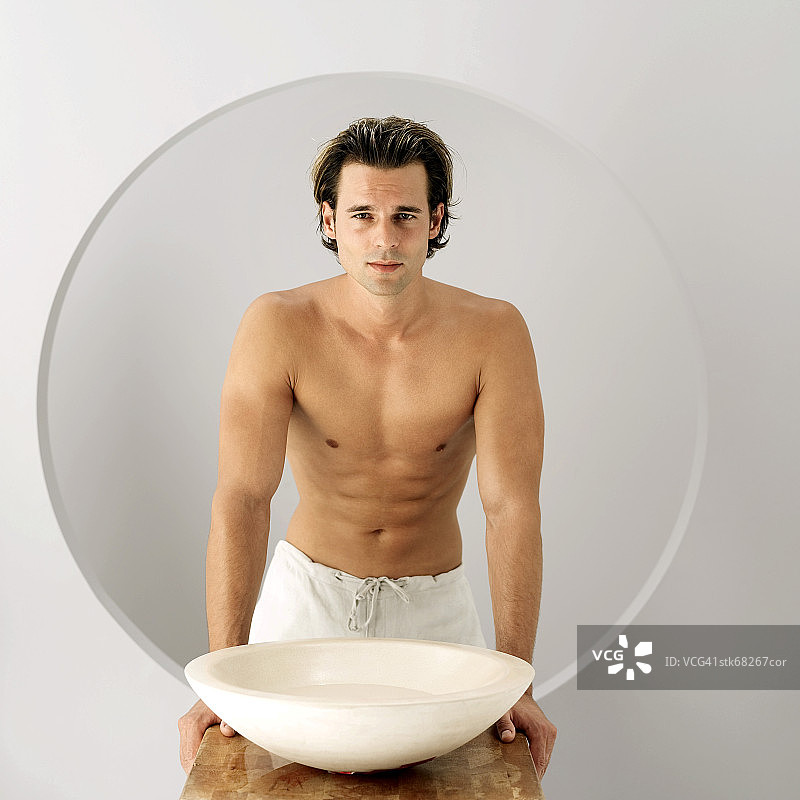 一个赤裸上身的年轻人端着一盆水的肖像图片素材
