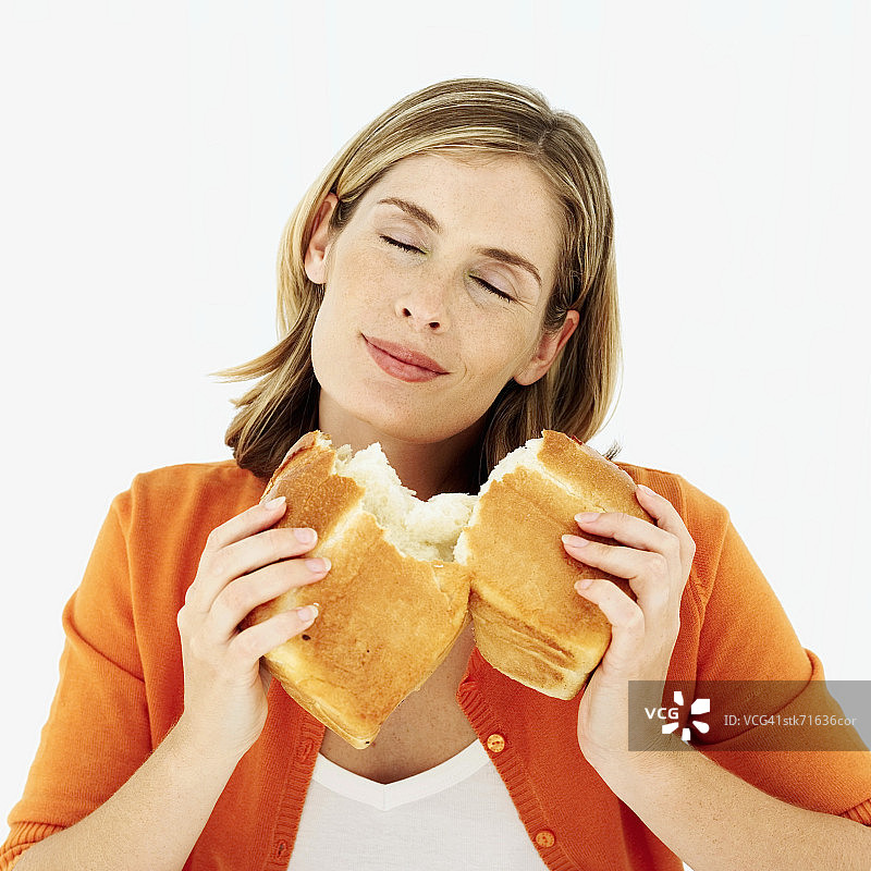 女人闻着一块碎面包图片素材