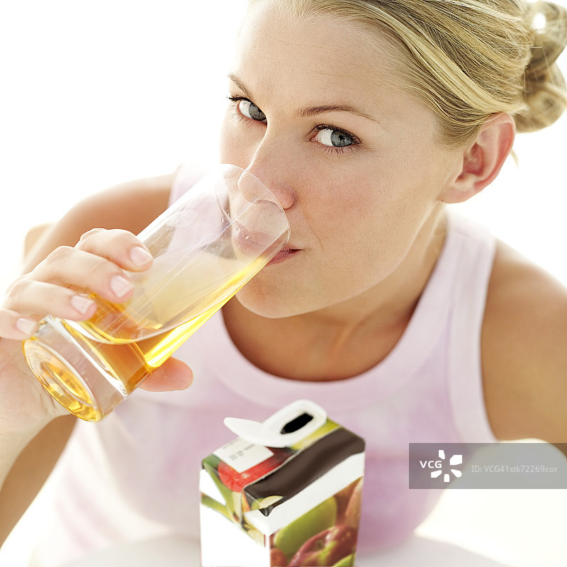 一个年轻女子喝着一杯苹果汁的肖像图片素材