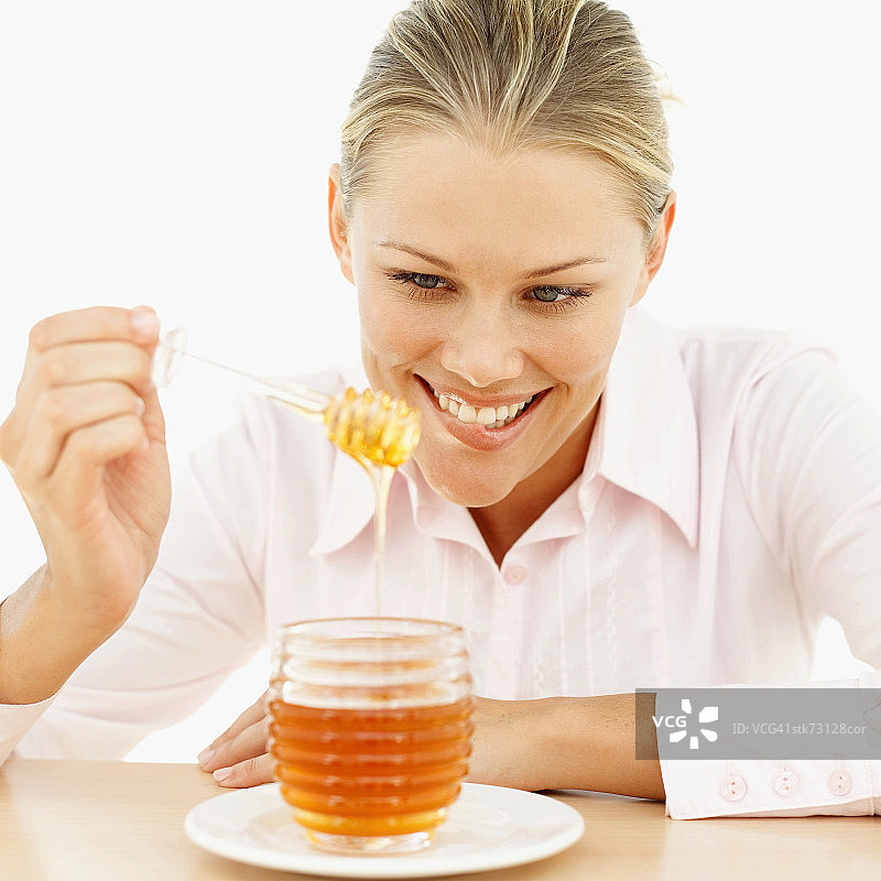 近距离拍摄：女人用蜂蜜勺舀蜂蜜图片素材