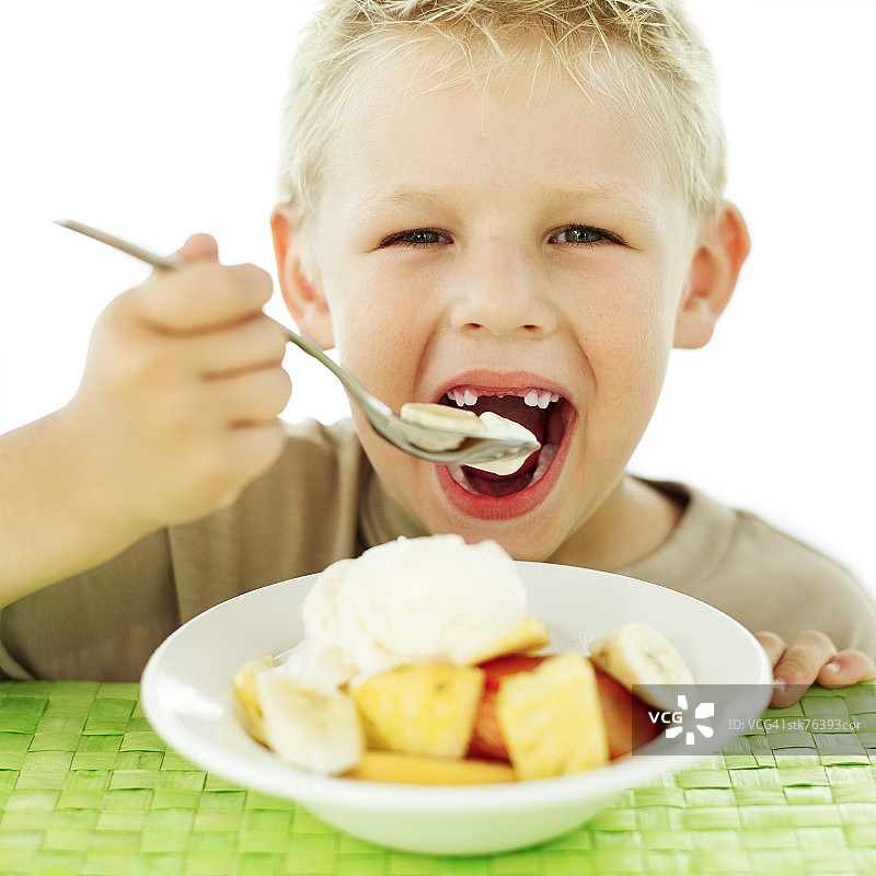 正在吃碗里水果的年轻男孩肖像图片素材