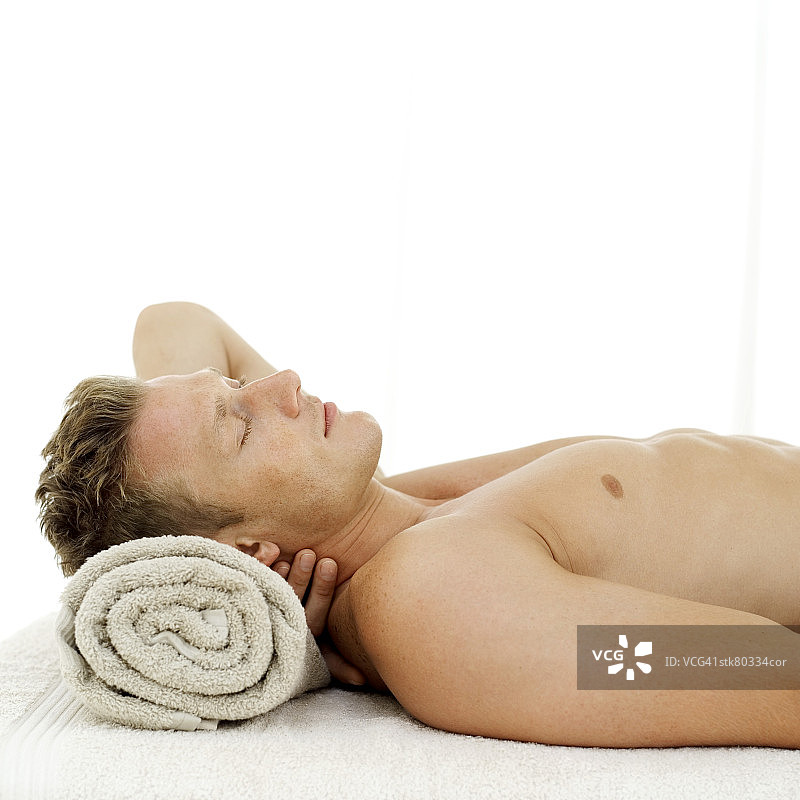 年轻男人用毛巾当枕头睡觉的侧面图片素材