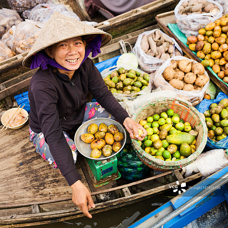 越南妇女在湄公河三角洲水上市场出售水果图片素材