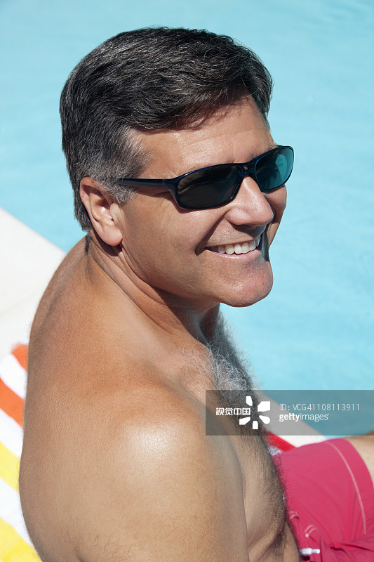 白人男子坐在游泳池旁。图片素材