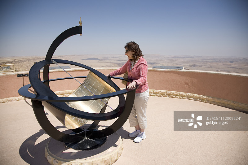 女性在以色列米茨佩拉蒙的拉蒙地质坑观看天文雕塑图片素材