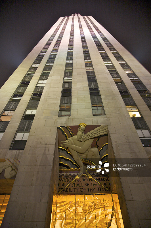 纽约洛克菲勒广场30号外观，入口上方有壁画，李·劳里的《智慧、光明与声音》夜景图片素材