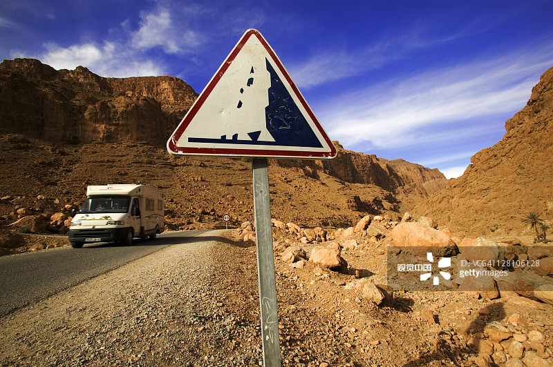 旅游车经过道路标志，警告人们在摩洛哥托德拉峡谷可能有落石图片素材