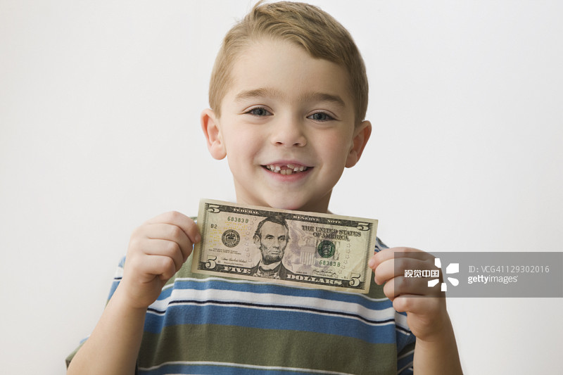 微笑的白人男孩拿着五美元钞票图片素材