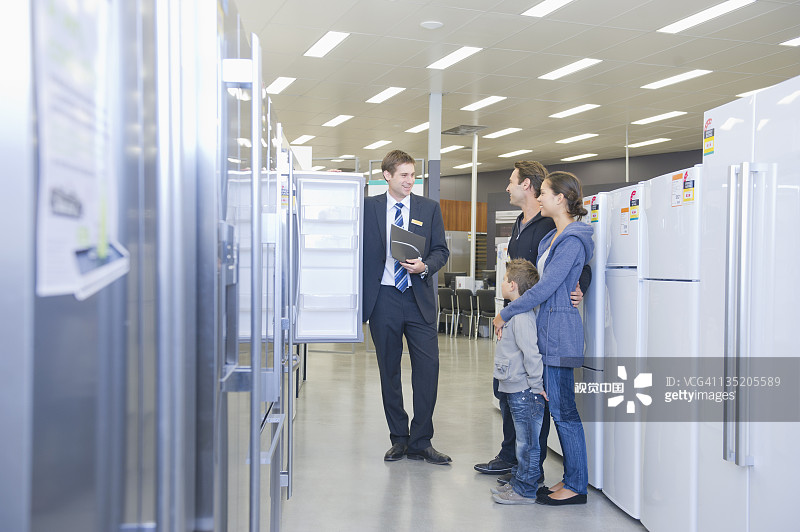 在电器部门与销售员交谈的西班牙裔家庭图片素材