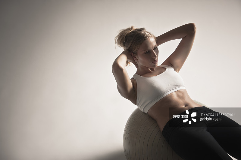 白人妇女在健身球上做仰卧起坐图片素材