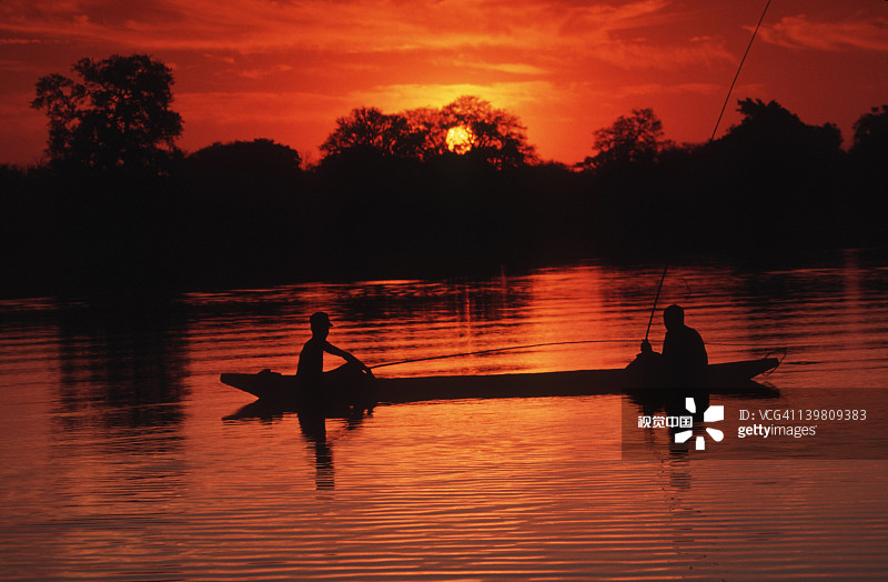 博茨瓦纳奥卡万戈三角洲日落时分的巴耶族独木舟撑篙人图片素材