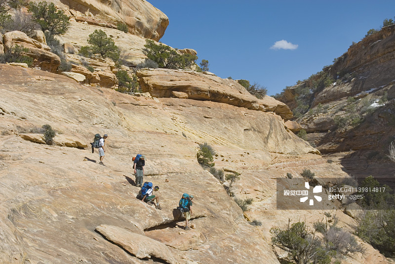 一群青少年背包客在犹他州雪松 mesa 子弹峡谷陡峭的岩石路段行走图片素材