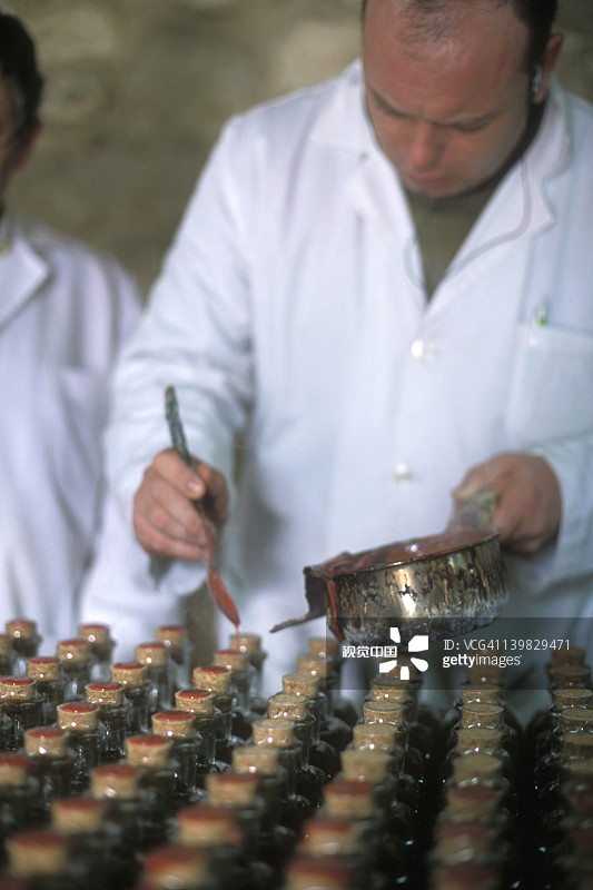 工人在西班牙南部安达卢西亚巴埃纳镇的Nunez de Prado工厂，用蜡封口装满有机特级初榨橄榄油的玻璃瓶图片素材