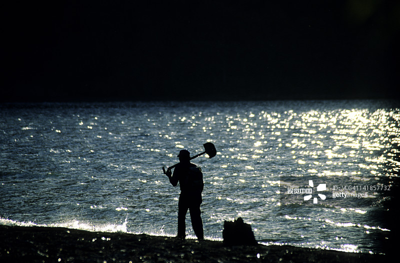 在智利比亚里卡湖上拿着铲子的男子剪影图片素材