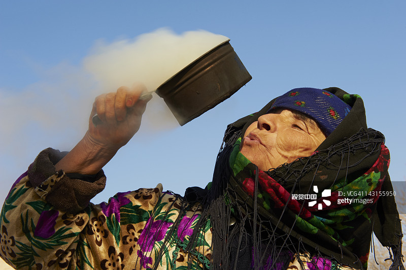 布哈拉，女人吹烟以驱除邪恶图片素材