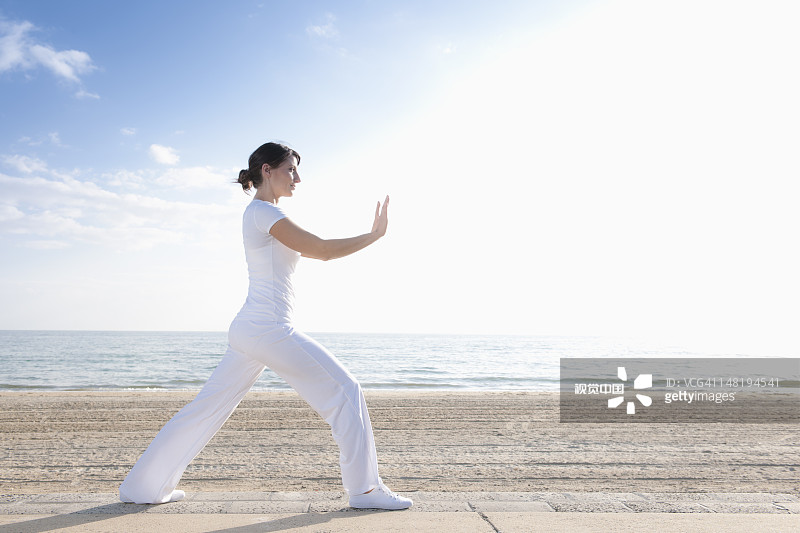 在海滩上练习瑜伽的西班牙裔女人图片素材