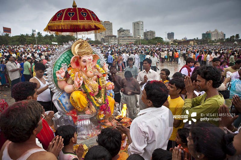 在象鼻神节期间，一家人在乔帕蒂海滩的象鼻神雕像前祭拜祈祷图片素材