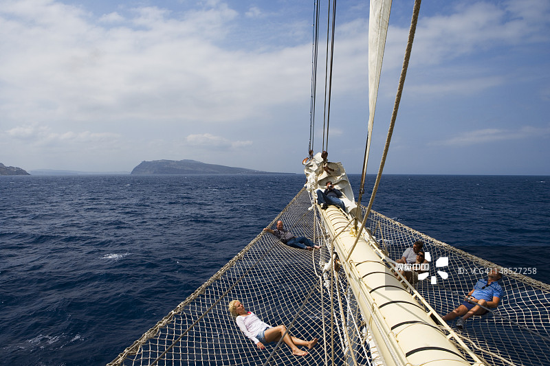 躺在星 clipper 号帆船游轮船首斜桅网上的乘客图片素材
