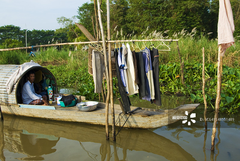 在湄公河三角洲的浮动房屋上的男人图片素材