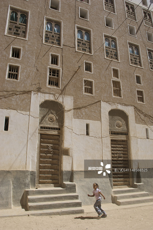 少女跑过希巴姆古城的塔楼图片素材