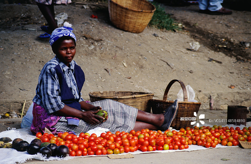 在街头市场卖西红柿的年轻女子。图片素材
