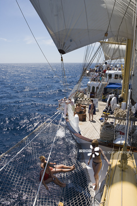 在地中海航行期间，人们在皇家快船号帆船的船首斜桅网上放松图片素材