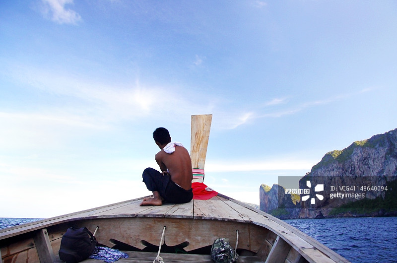 男人坐在长船的前面图片素材