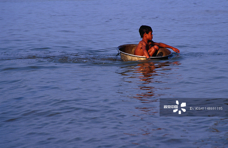 男孩在洞里萨湖Chong Kneas水上村庄的大碗里钓鱼图片素材
