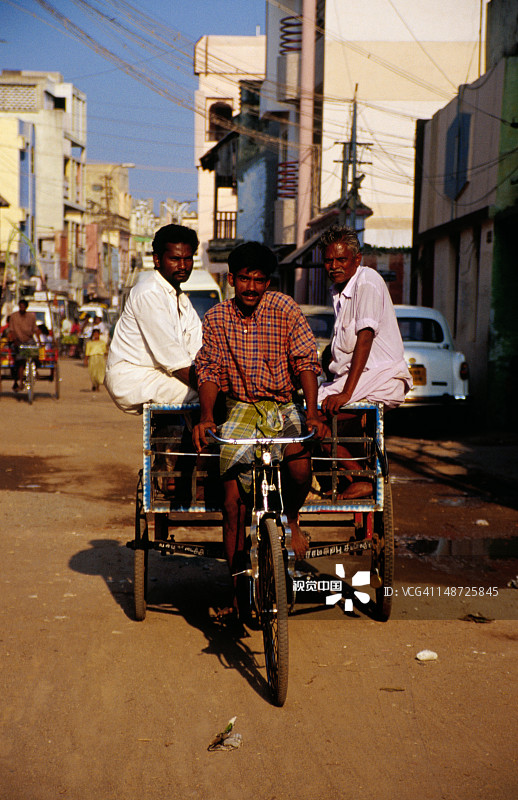 男人用自行车拉着两名乘客图片素材