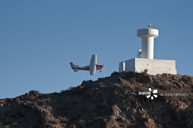 灯塔附近飞行的小飞机图片素材