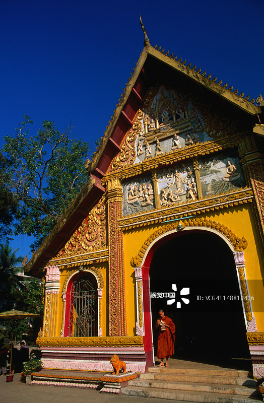 僧侣站在西蒙寺入口，门楣上的雕刻描绘了佛陀的生活场景图片素材