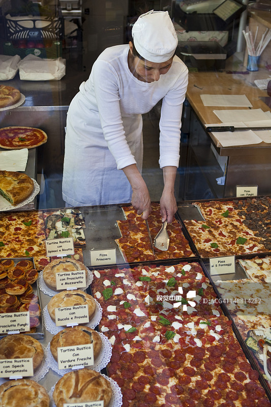 女人在咖啡馆的窗户里切披萨图片素材