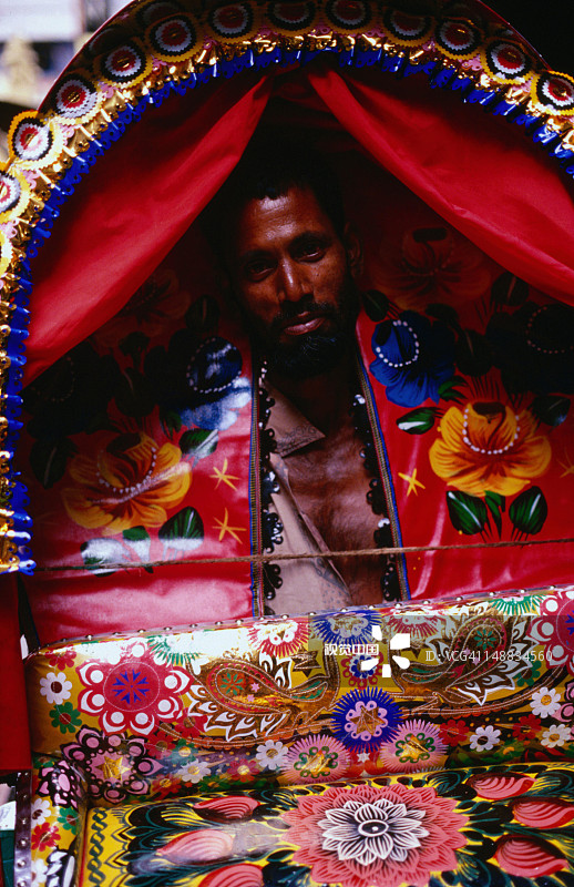 一名人力车夫透过他的车辆的窗户偷看，据说孟加拉国的人力车是最华丽的，达卡图片素材