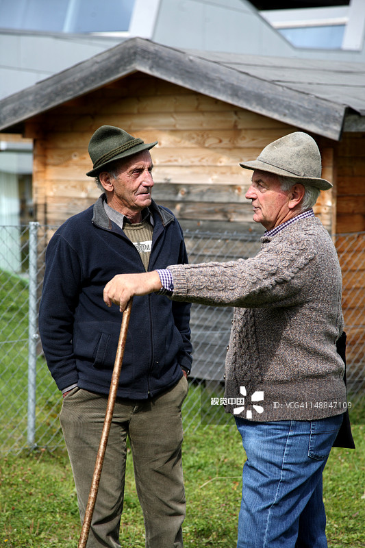 在阿尔卑斯山赶牛节上，两位戴着传统洛登帽的农民互相交谈图片素材