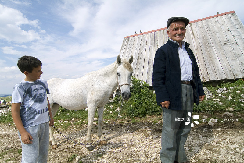 男人和男孩在黑山共和国的乡村与白马图片素材