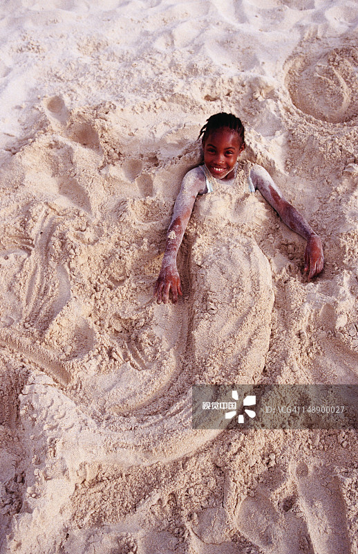 在格兰德安斯海滩上，一个年轻女孩身上盖满了沙子，呈美人鱼形状图片素材