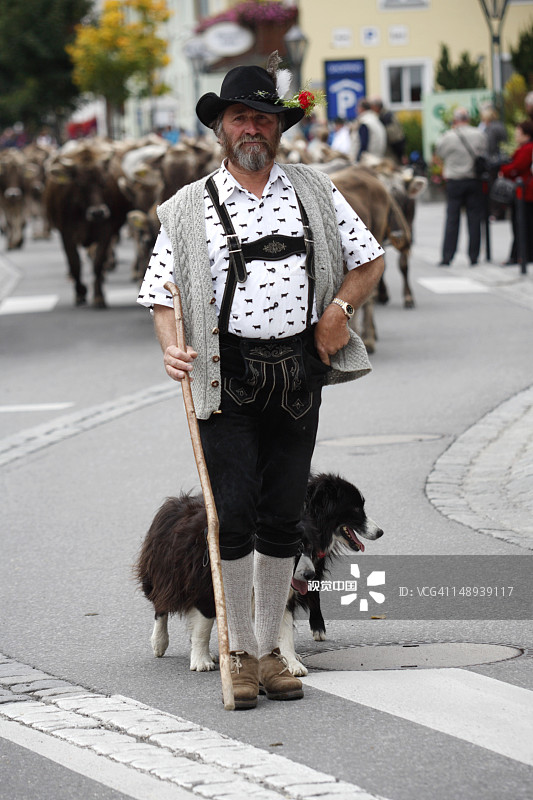 穿着传统服饰的牧民带着他的狗参加高山牛赶集节日的游行图片素材