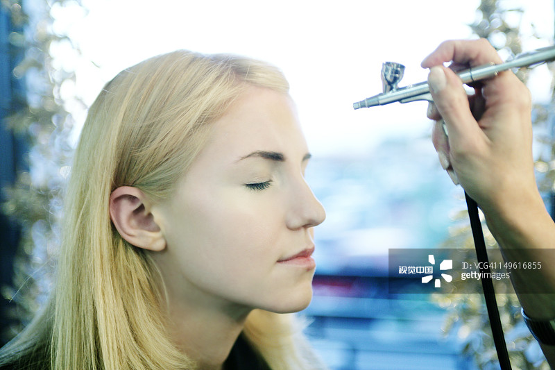 一个脸上被喷了化妆品的女人图片素材