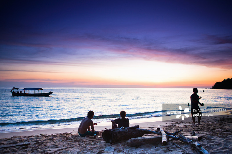 旅行者在海滩上放松身心欣赏日落图片素材