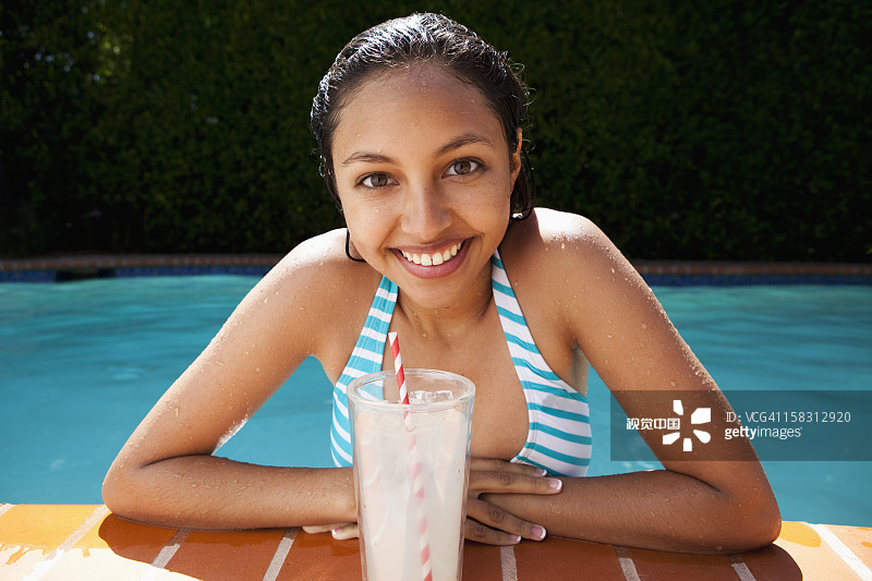 混血女孩在游泳池旁喝柠檬水图片素材