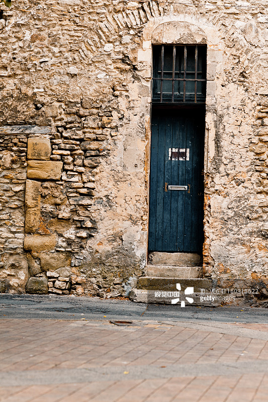 石灰石墙上的蓝色旧门图片素材