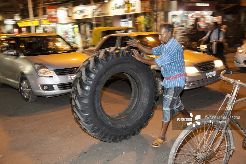 在印度加尔各答街头送轮胎的男人图片素材