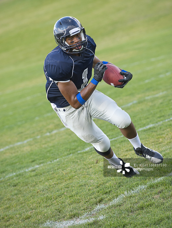 抱着球的非裔美国橄榄球运动员图片素材