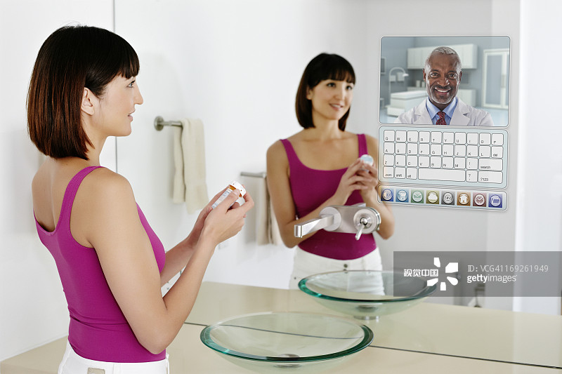 在镜子中使用电脑的混血女人图片素材