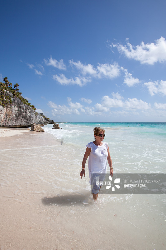 女人在图卢姆遗址附近的海滩上漫步图片素材