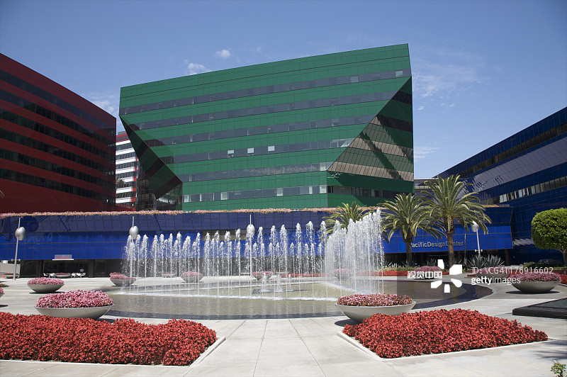 喷泉和红色植物旁的绿色建筑图片素材