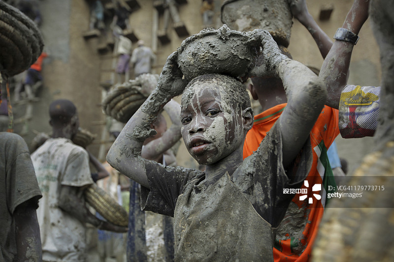 泥泞中，男孩们在清真寺扛着石膏图片素材