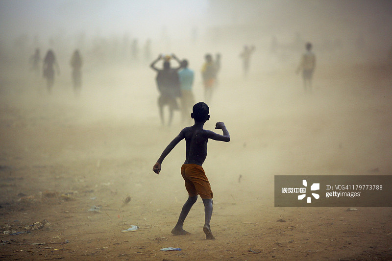 男孩在杰内城的干燥多尘的沙漠中玩耍图片素材