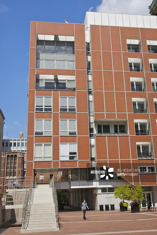 在橙色建筑物附近行走的年轻男人图片素材